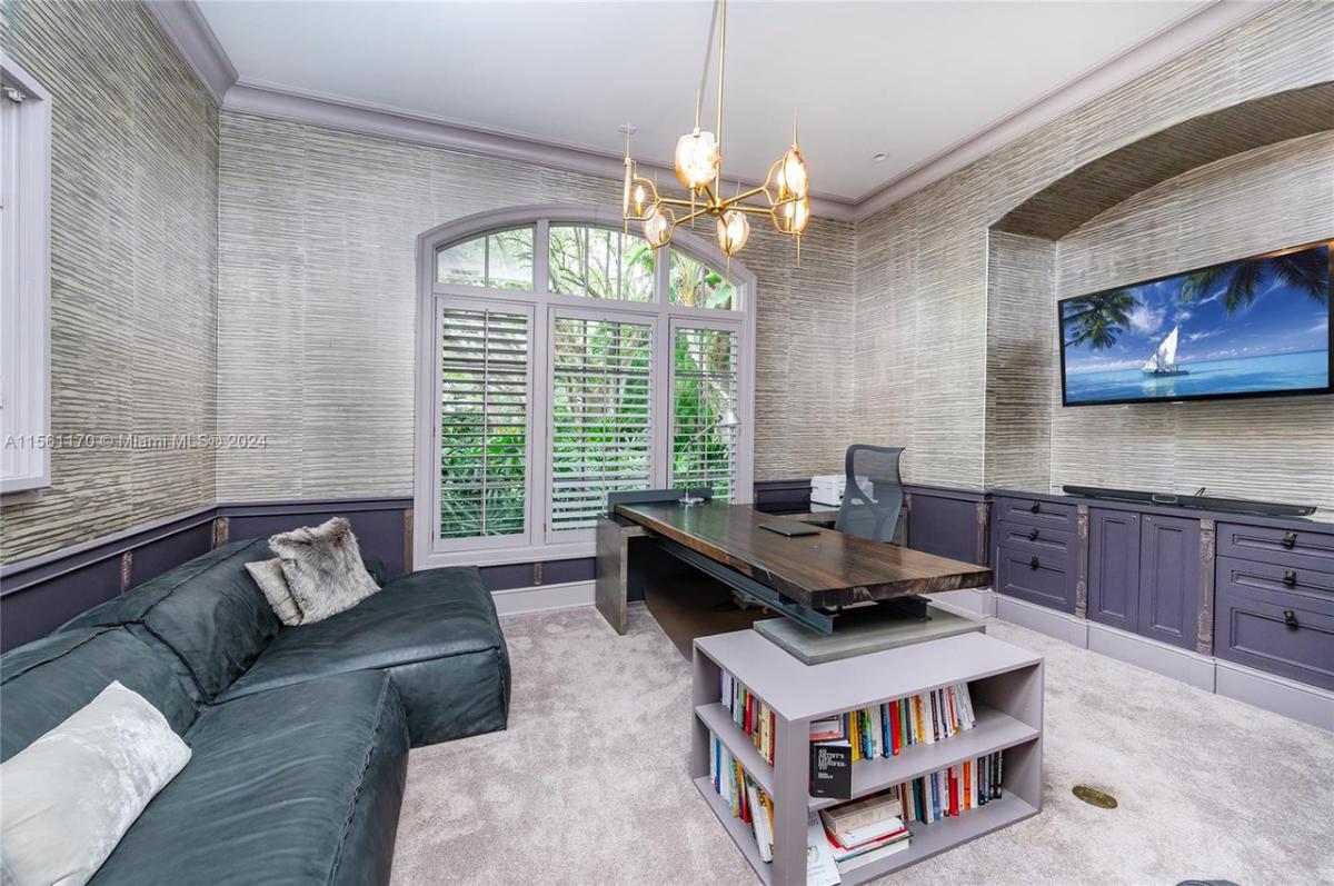 Home office with a couch, chandelier and a TV.