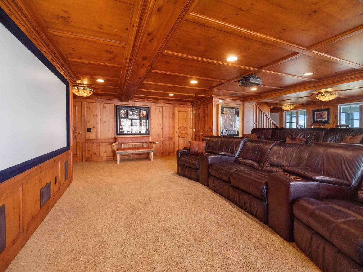 Home theater with a large screen, couches, carpet flooring and custom lights.