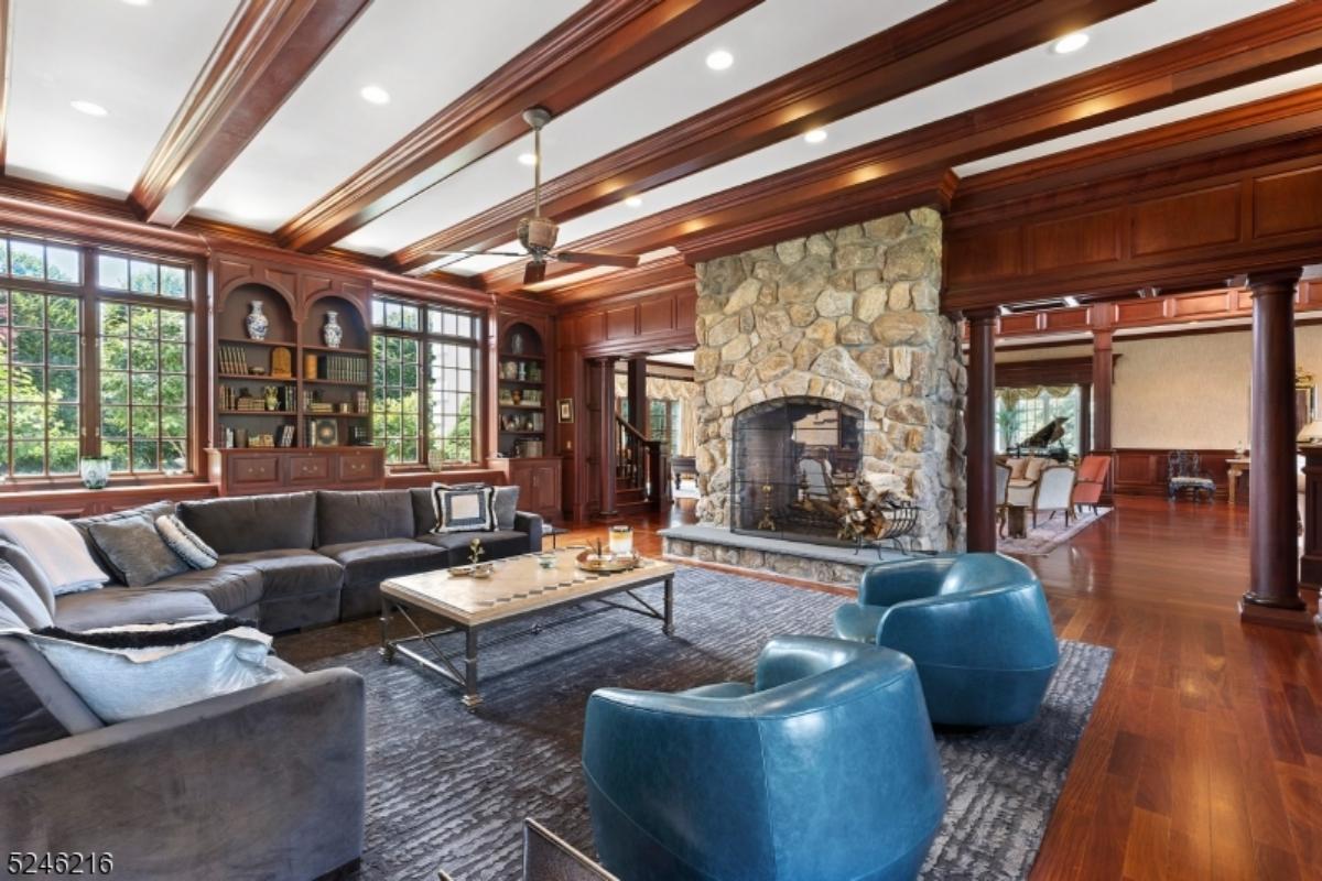 Living room with a couch, glass windows, fireplace and a large rug.
