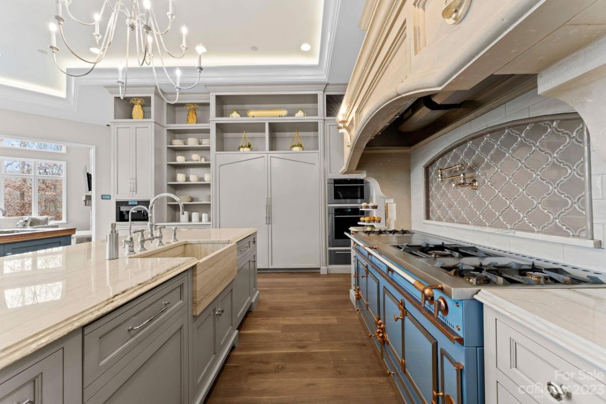 Kitchen with a large island, wooden floor, stove and custom cabinets.