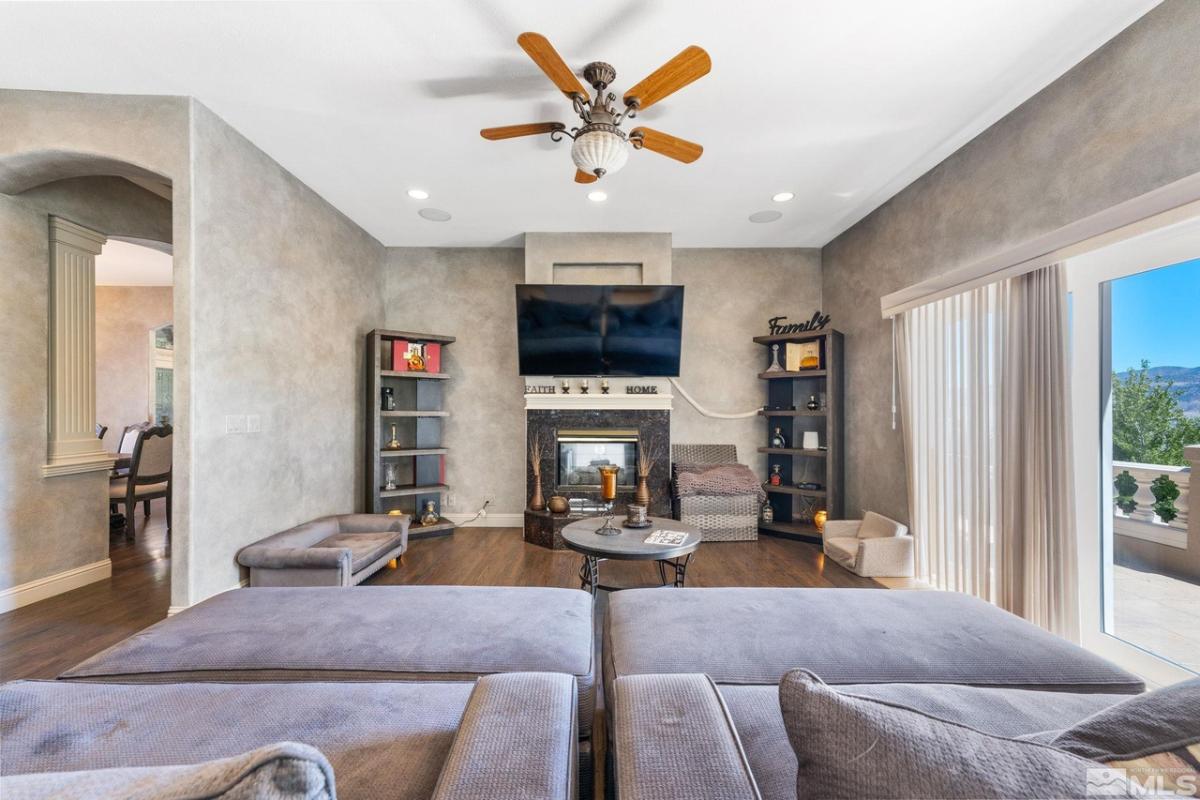 Living room with couches, TV, glass doors, fireplace and custom lights.