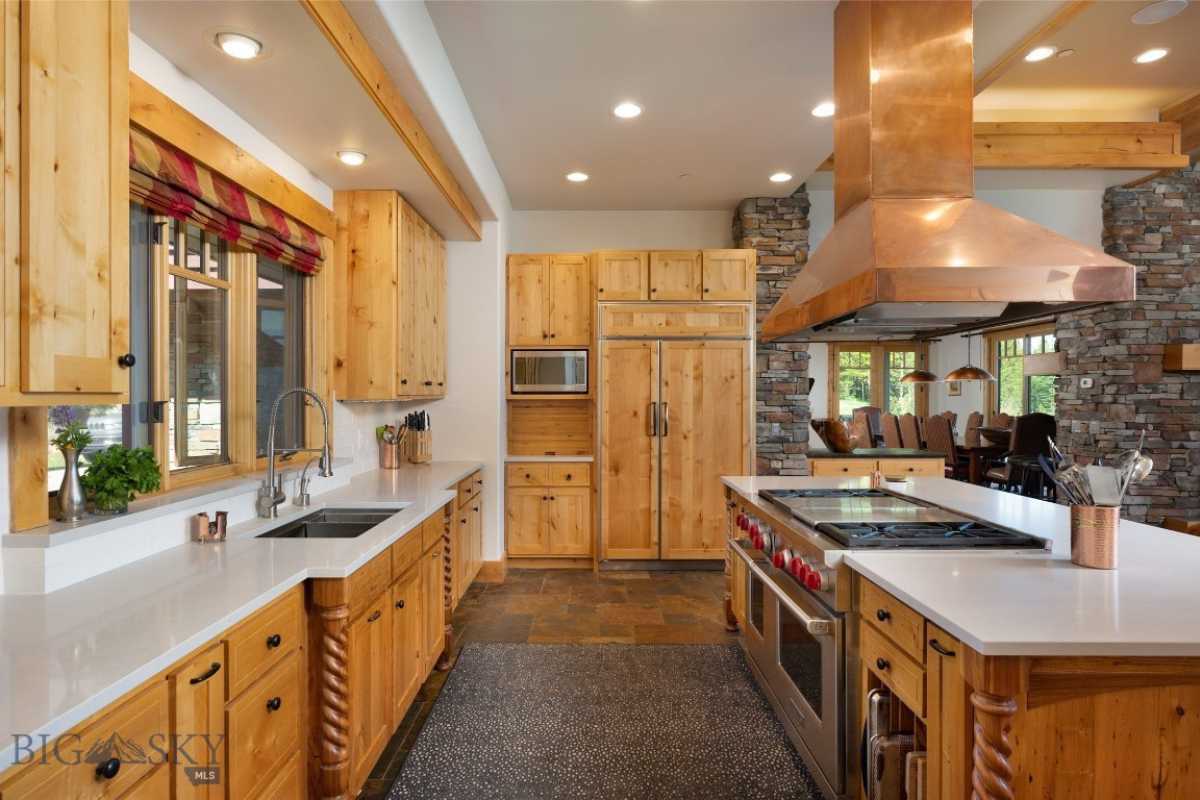 A kitchen with a countertop, sink, wooden cabinets, and kitchen appliances.