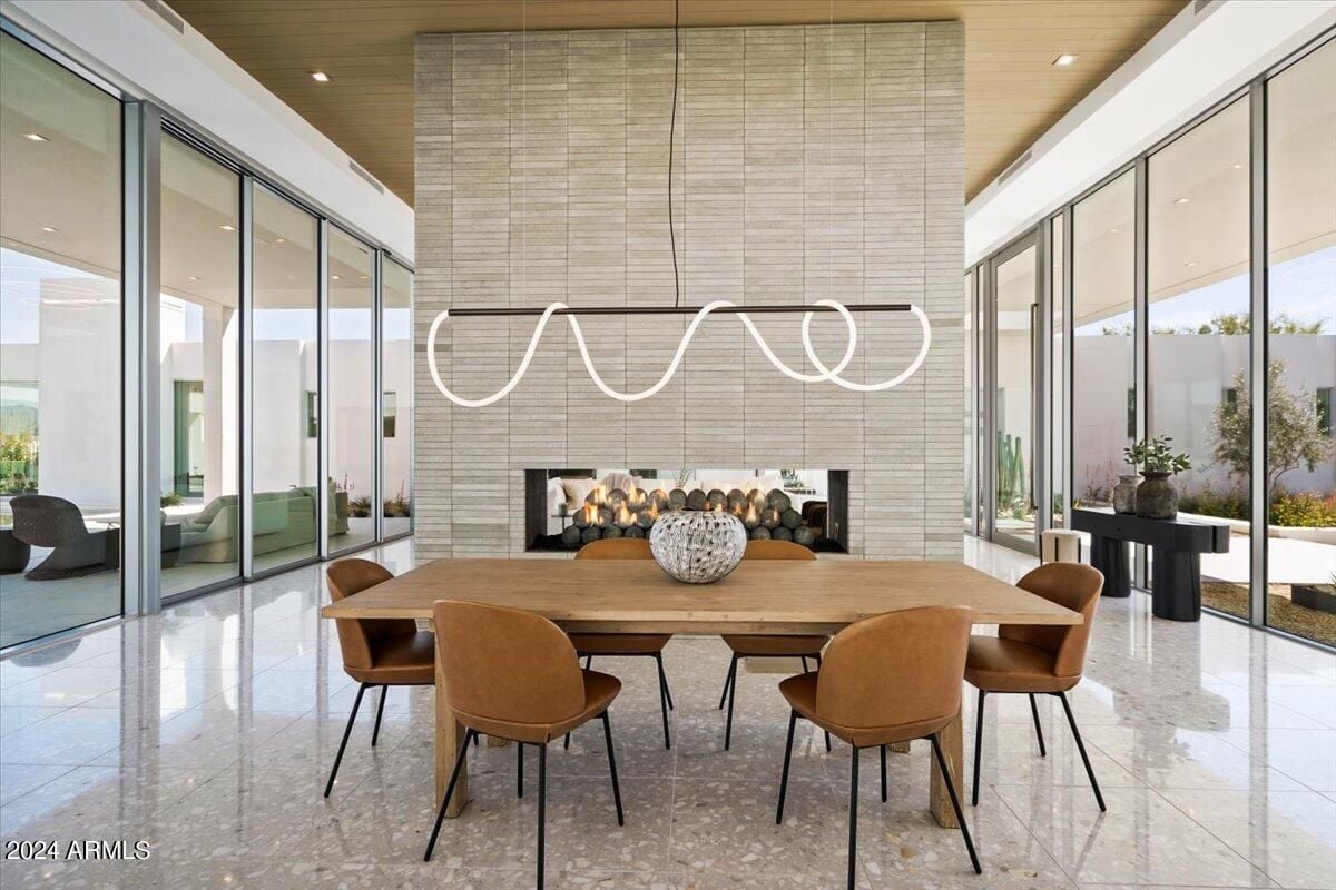 A dining room with a tiled floor, firepit, and dining table surrounded by chairs.