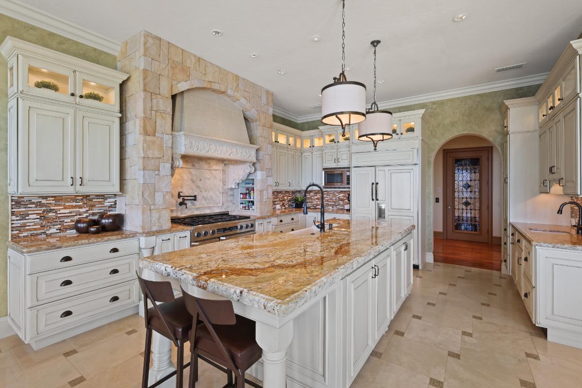 Kitchen with a large island, stove, sink and custom cabinets.