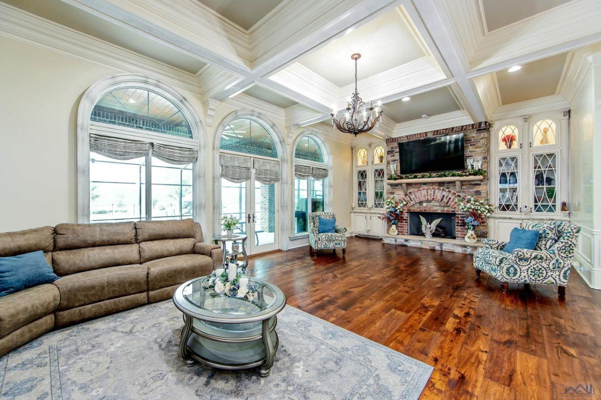 Living room with couches, TV, glass doors, glass windows, fireplace and a large rug.