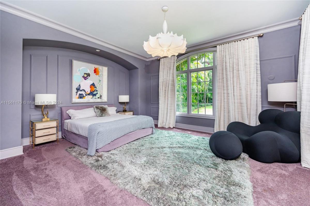 Bedroom with carpet flooring, chandelier and glass windows.