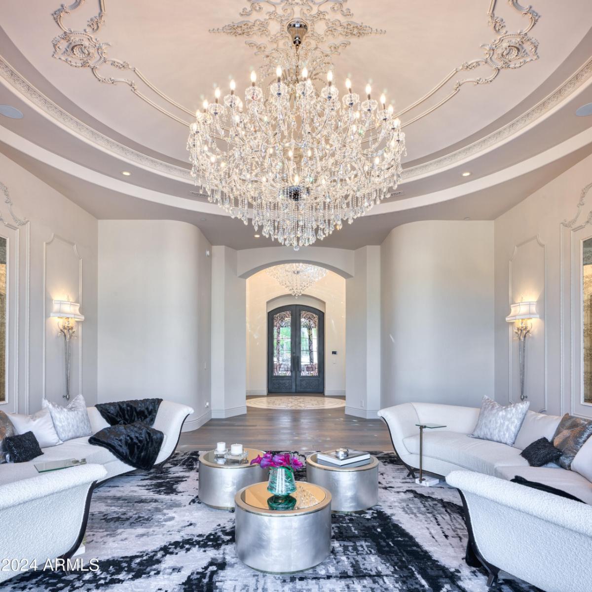 Living room with couches, chandelier and a large rug.