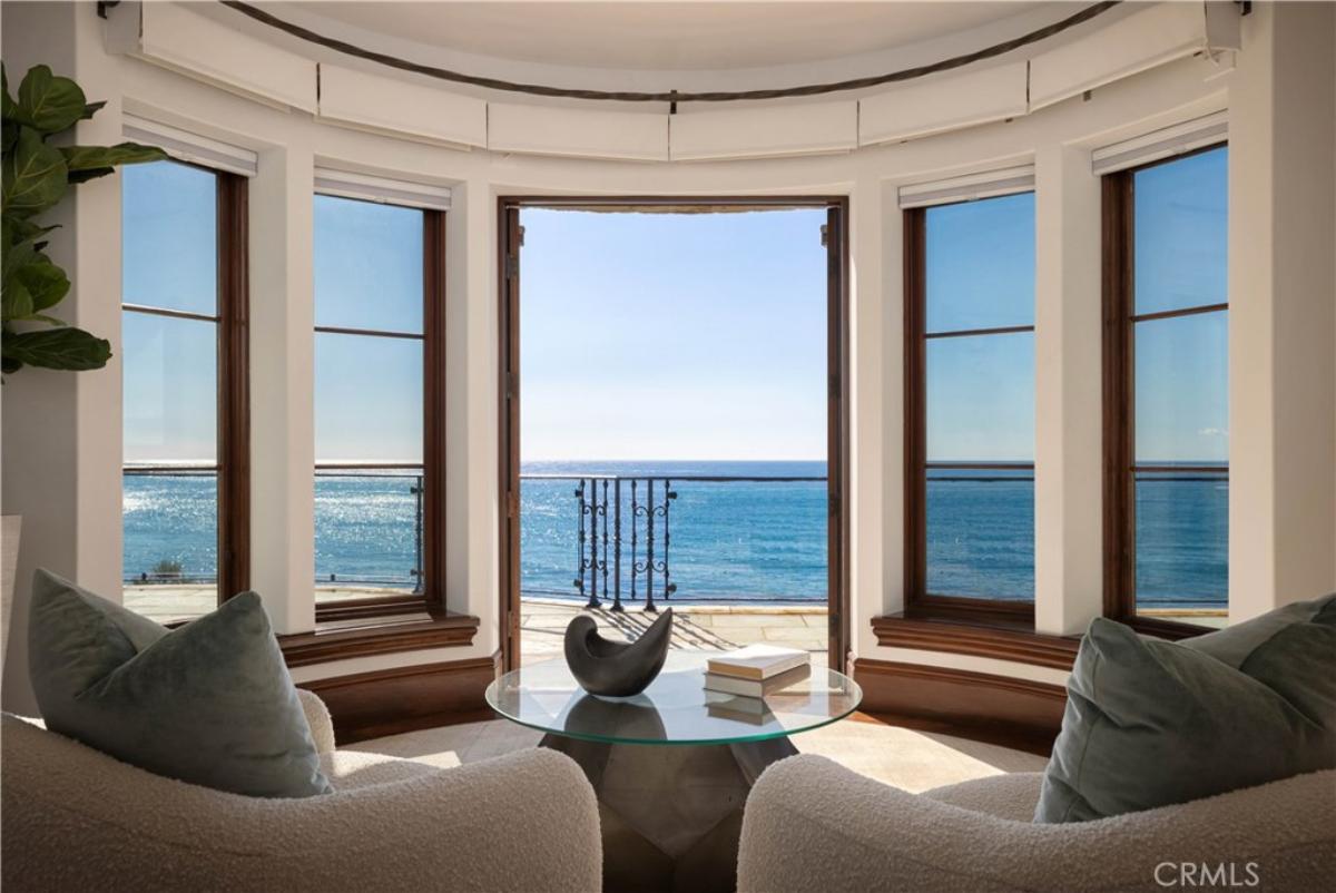 Sitting area of a bedroom with glass windows overlooking the ocean.