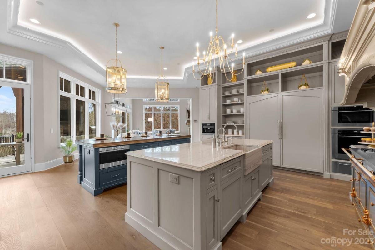 Kitchen with a large island, wooden floor and custom lights.