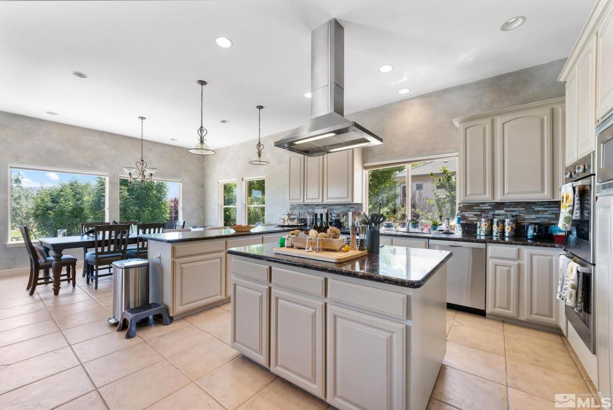Kitchen with a large island, tile flooring, custom lights and custom cabinets.