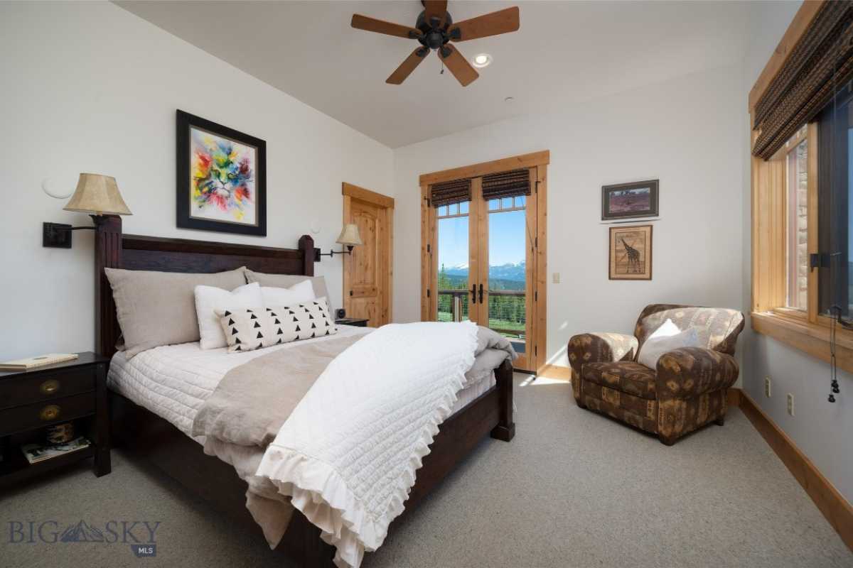 A bedroom with white walls, a white ceiling, a ceiling fan, a couch, a bed, and a nightstand.