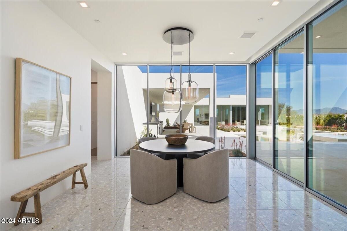 A breakfast nook with a painting, tiled floor, bench, and a table surrounded by chairs.