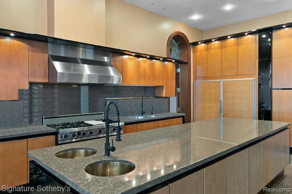 A kitchen with an island, a sink, wooden cabinets, and wooden cabinets.