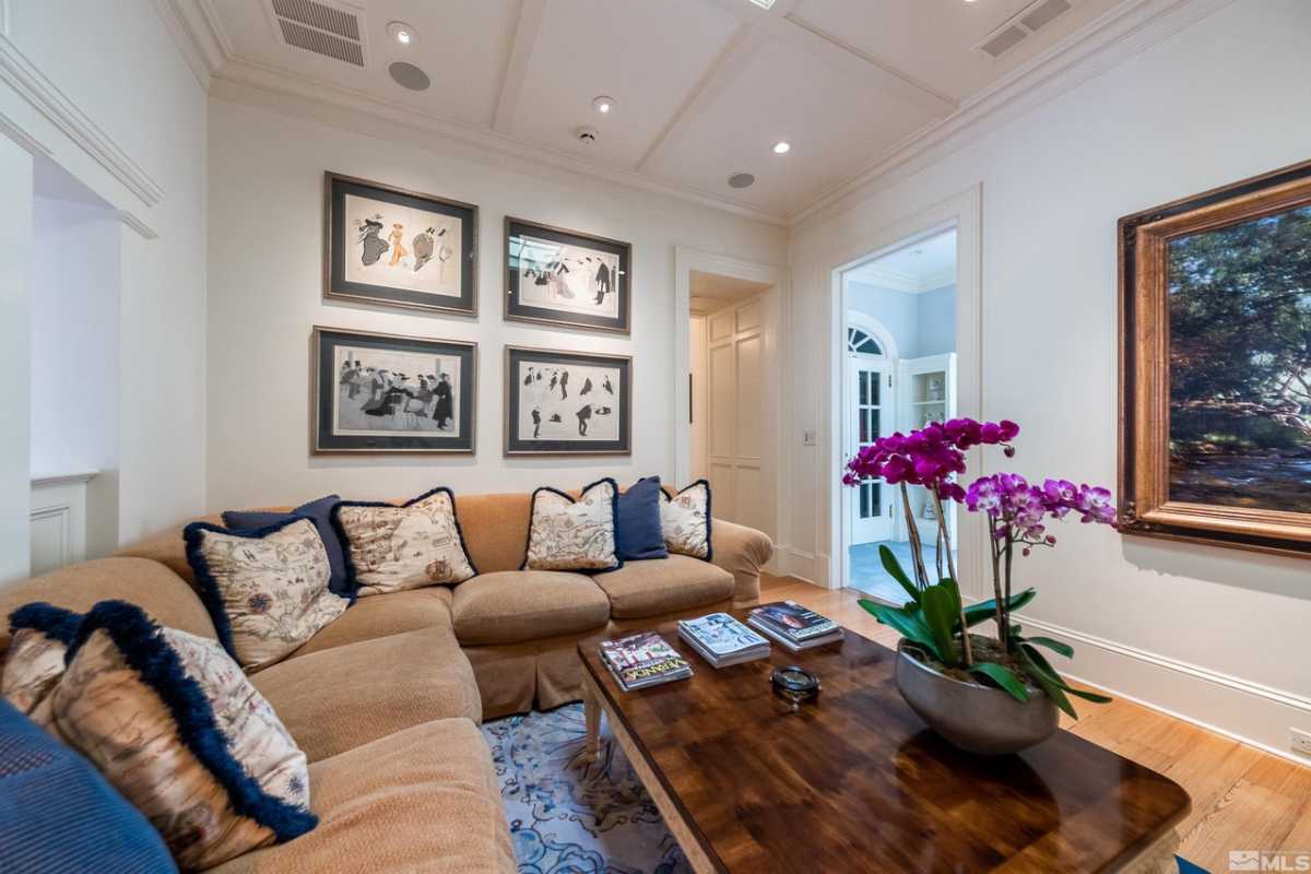 A family room with a couch, pillows, paintings, and a flower vase atop the coffee table.