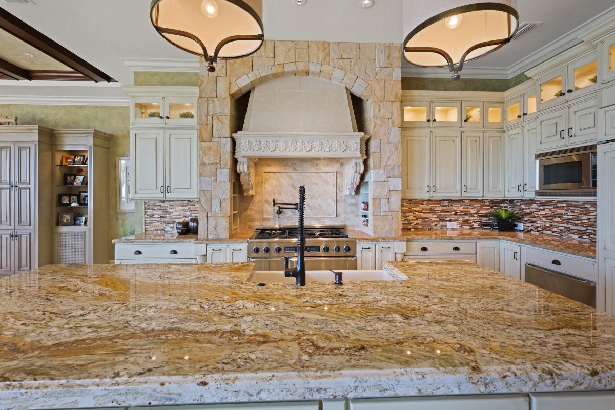 Kitchen with a large island, stove, custom lights and custom cabinets.