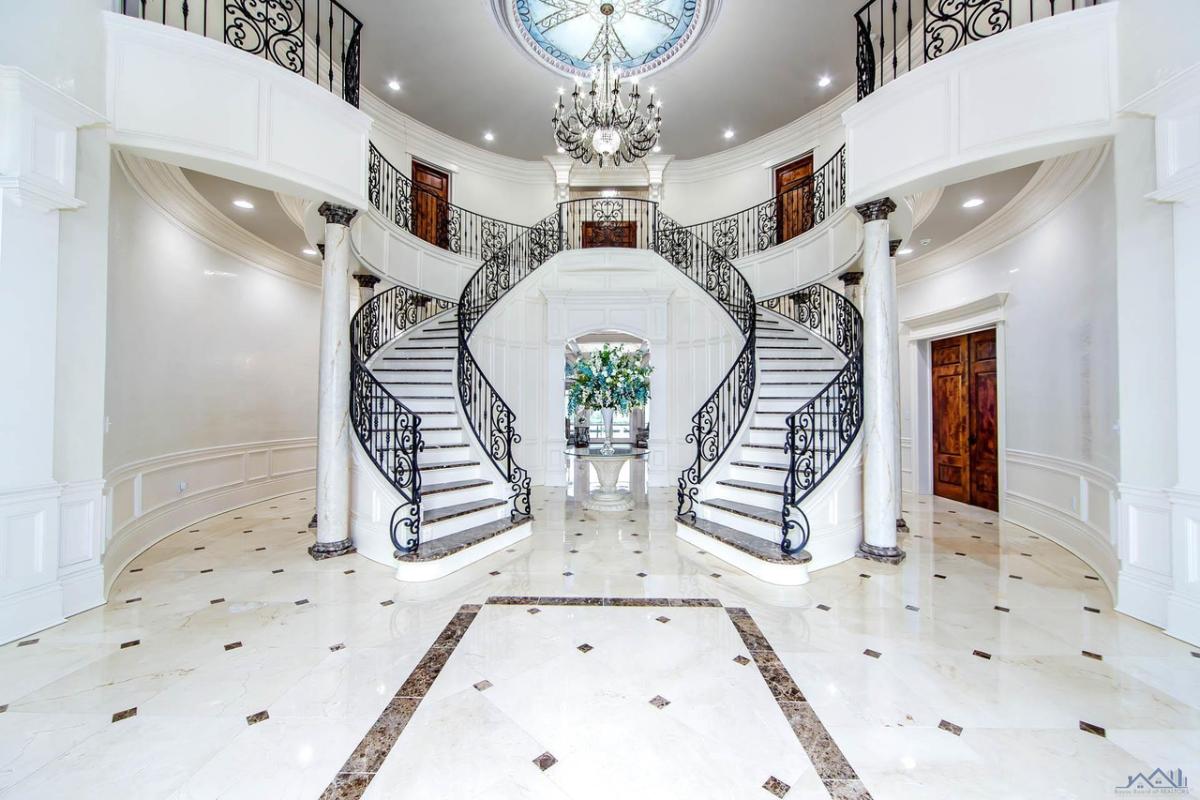 Foyer with a chandelier, custom lights and staircase.