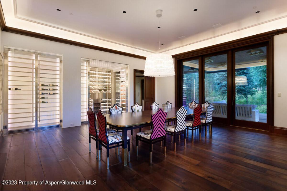 Dining room with a large table, chairs, chandelier and a wood flooring.