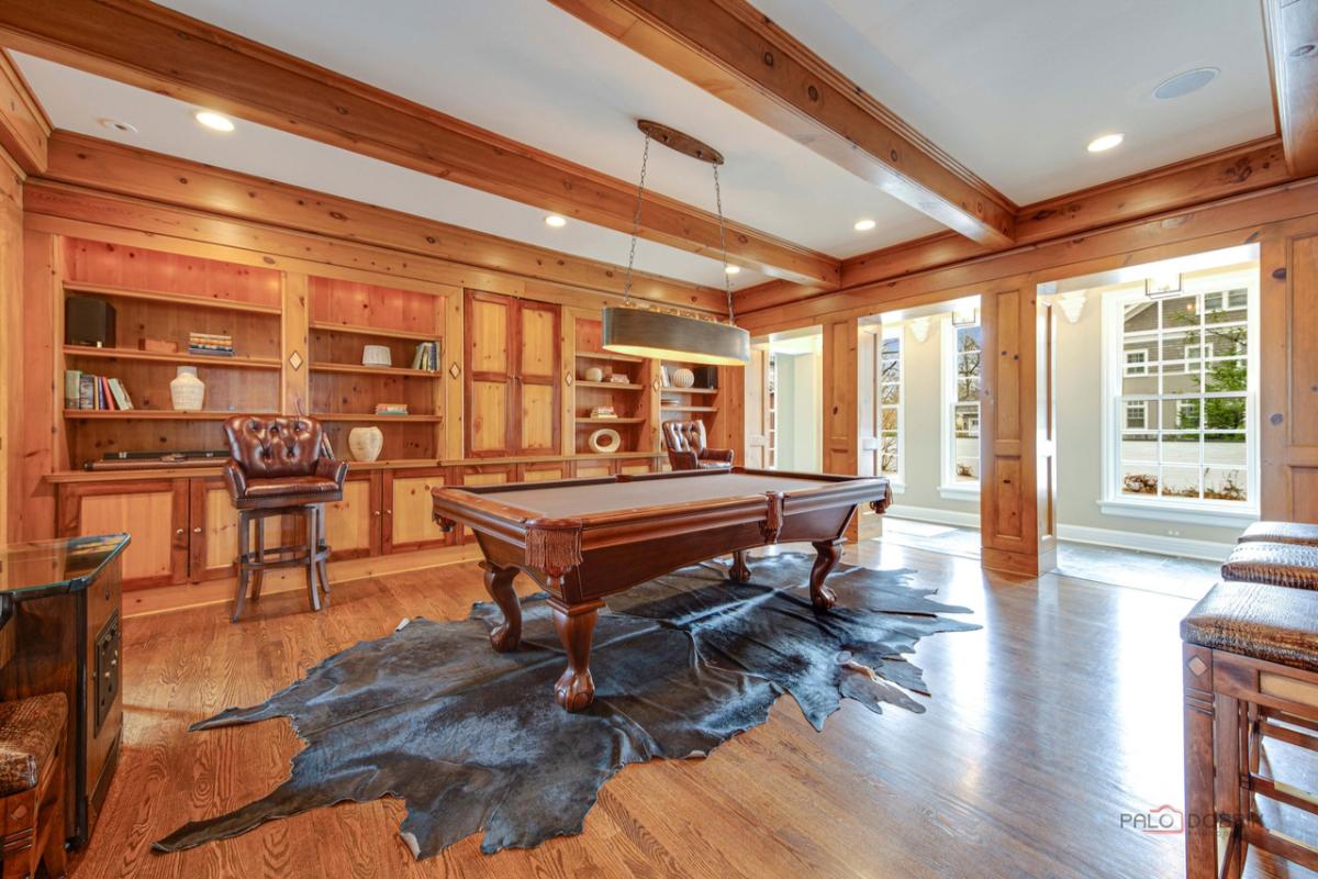 Game room with a billiard table, wooden floor and custom lights.