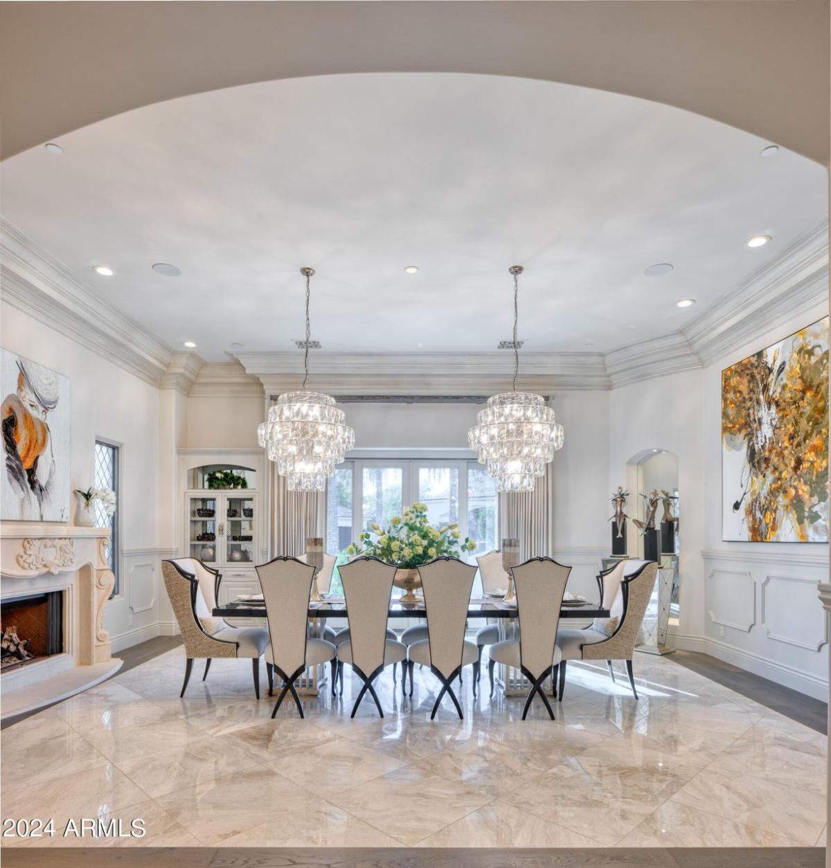 Dining room with a large table, chairs, chandelier and a fireplace.