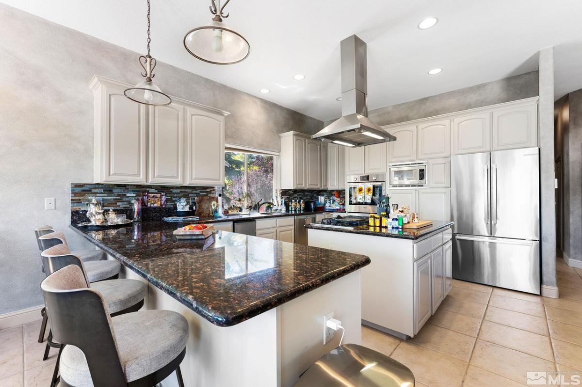 Kitchen with a large island, tile flooring, custom lights and custom cabinets.