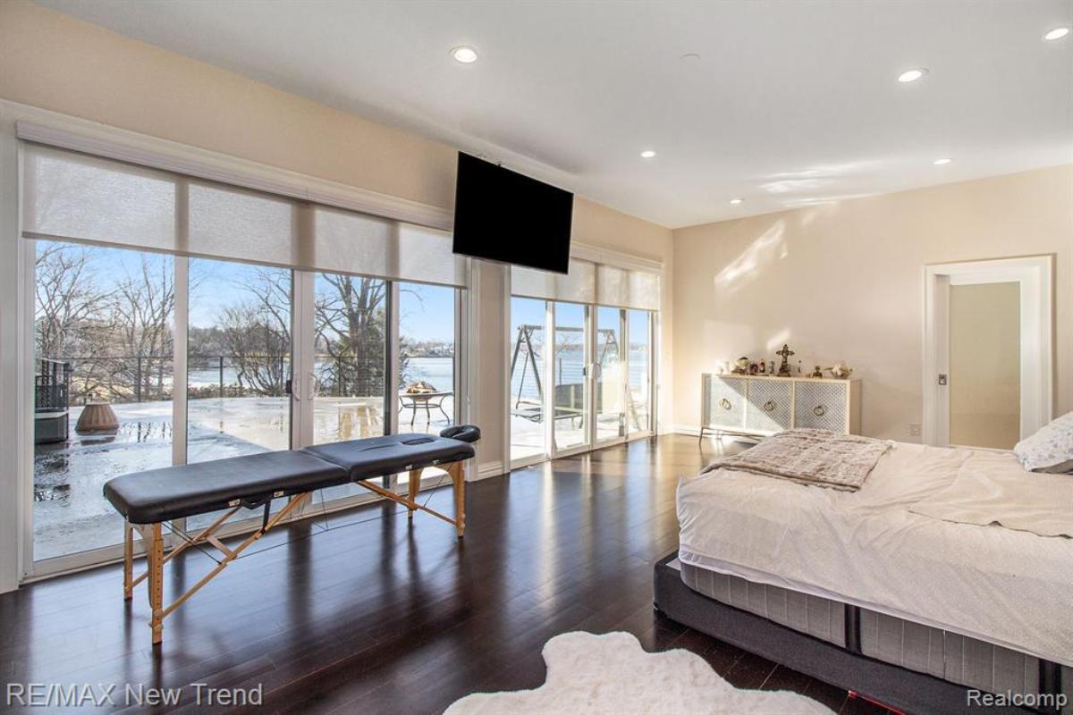 Bedroom with a large bed, TV and large glass windows.