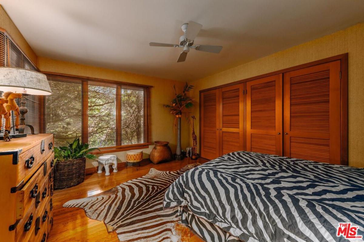 Bedroom with a large bed, wooden floor, glass windows and a large rug.