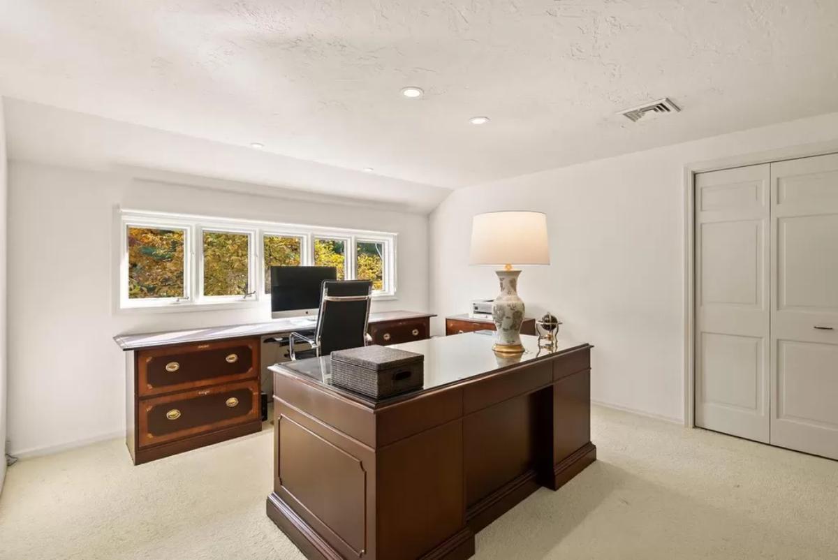 Home office with wooden desks and carpet flooring.