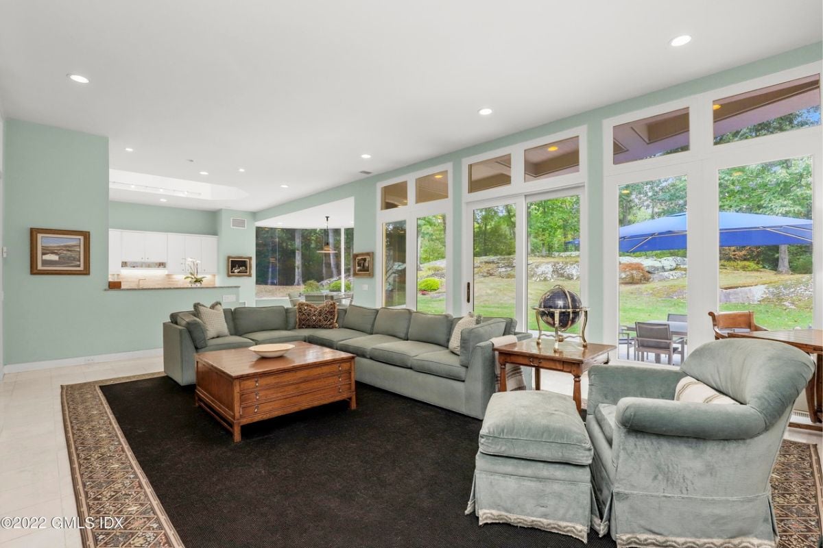 A lounge with a rug, windows, a white ceiling, couches, and a coffee table.