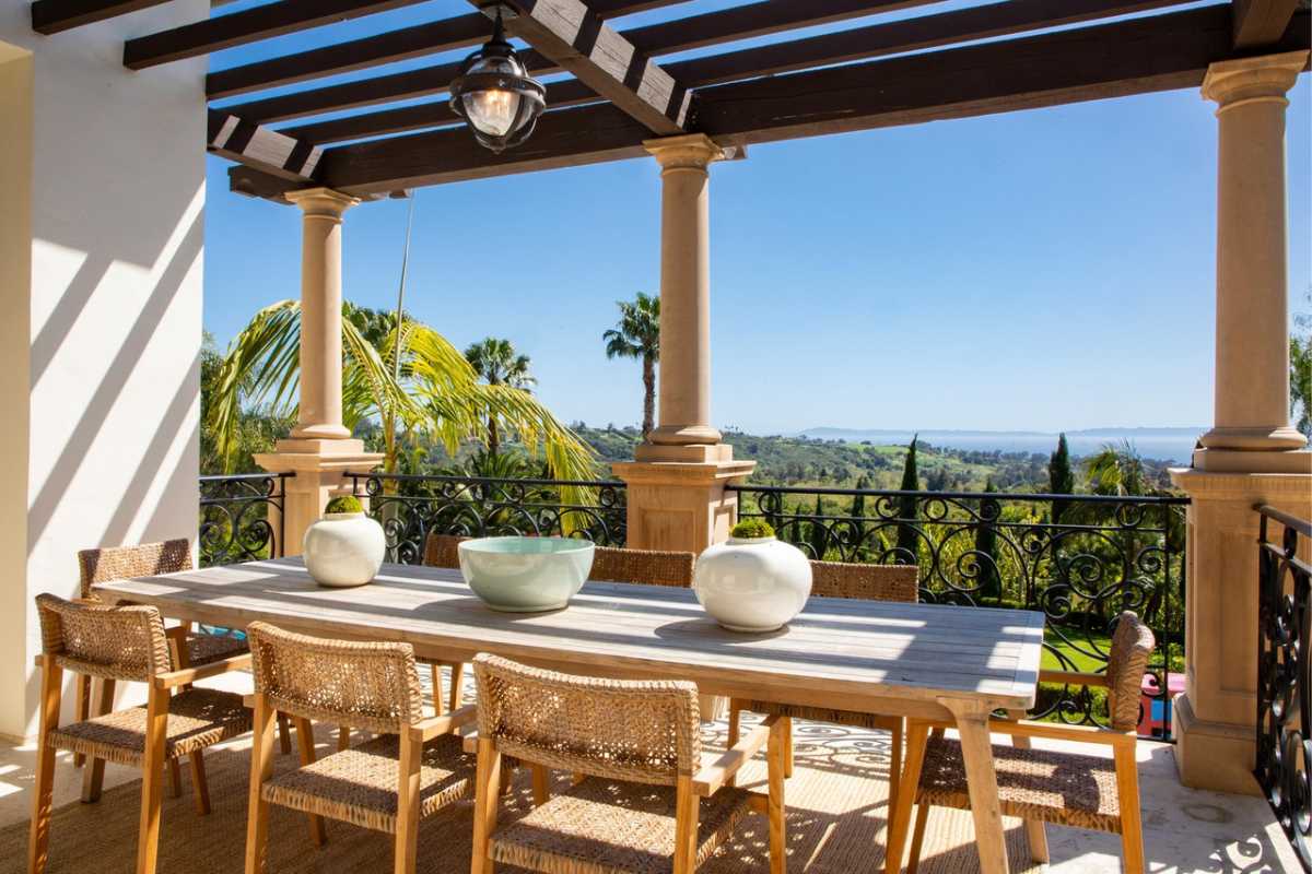 An outdoor dining area with a wooden table surrounded by chairs.
