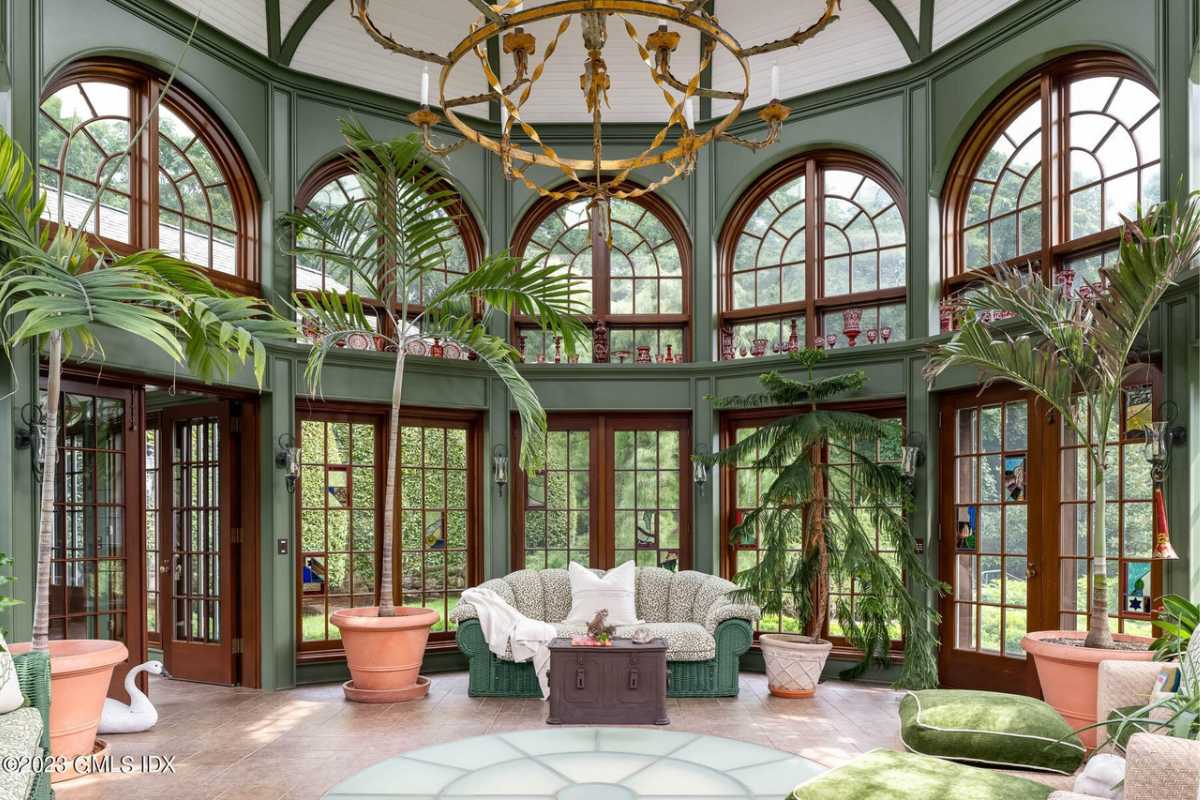 A sunroom with plants, windows, a couch, and a coffee table.
