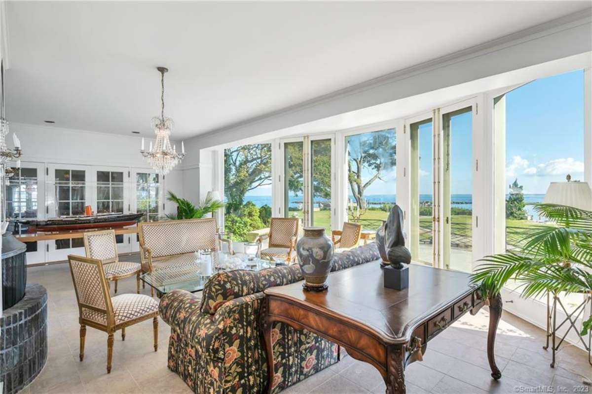 A covered porch with a table, chairs, a couch, a coffee table, and a white ceiling.