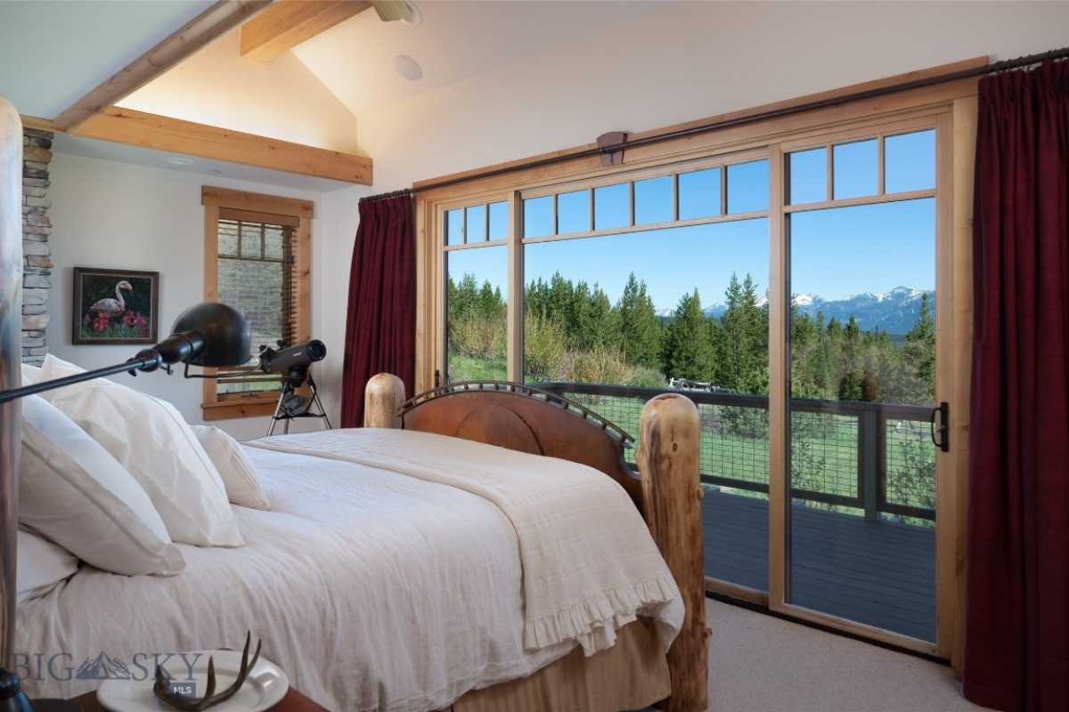 A bedroom with a bed, painting, window with a curtain, and beamed ceiling.