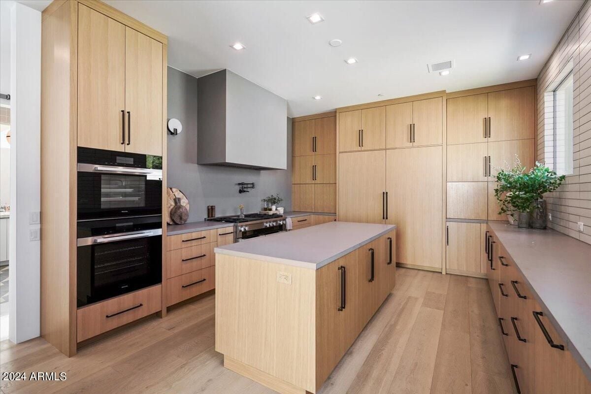 A kitchen with a center island, wooden floor, wooden cabinets, and kitchen appliances.