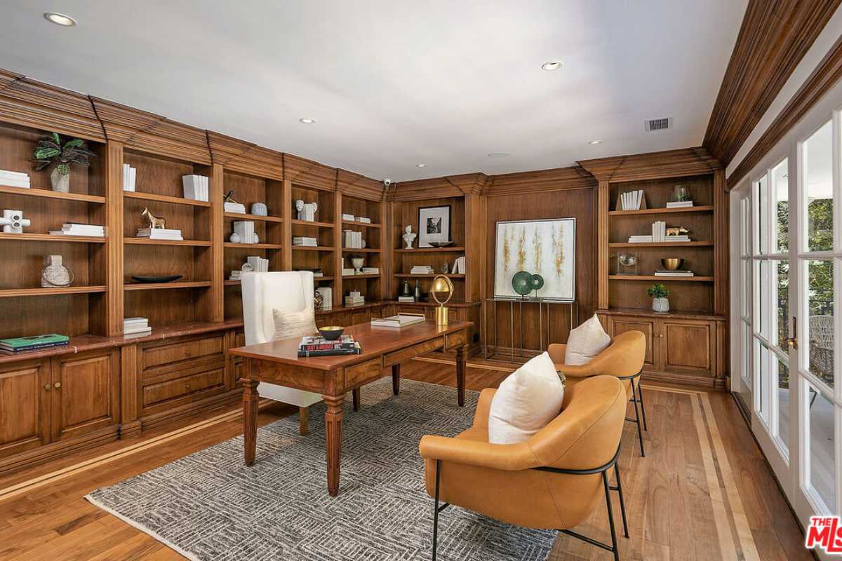 A home office with a wooden floor, rug, shelves, cabinets, a white ceiling, desk, and chairs.