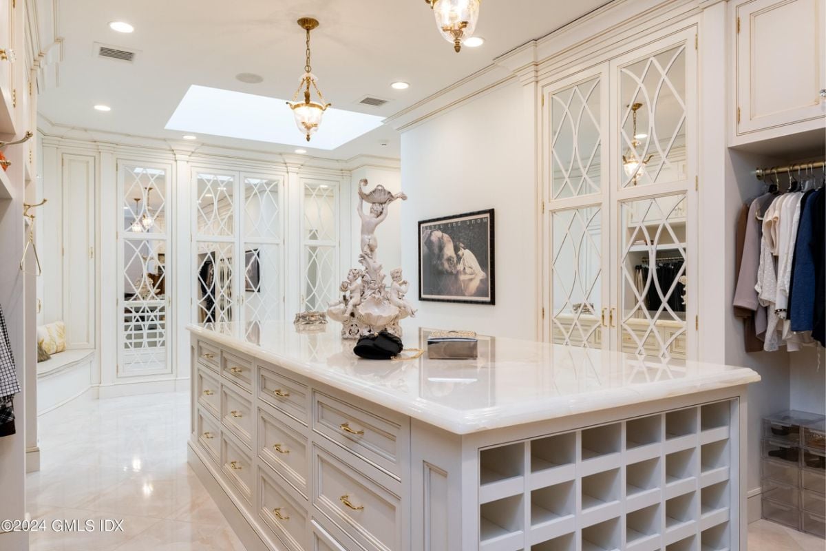 A walk-in closet with a large center island, tiled floor, cabinets, white ceiling, and lighting.