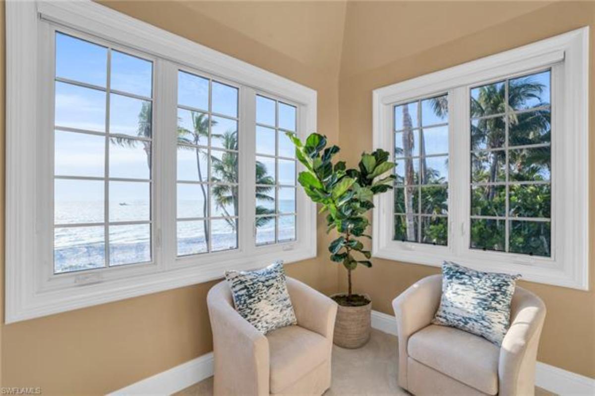 Sitting area with chairs and glass windows overlooking the ocean.