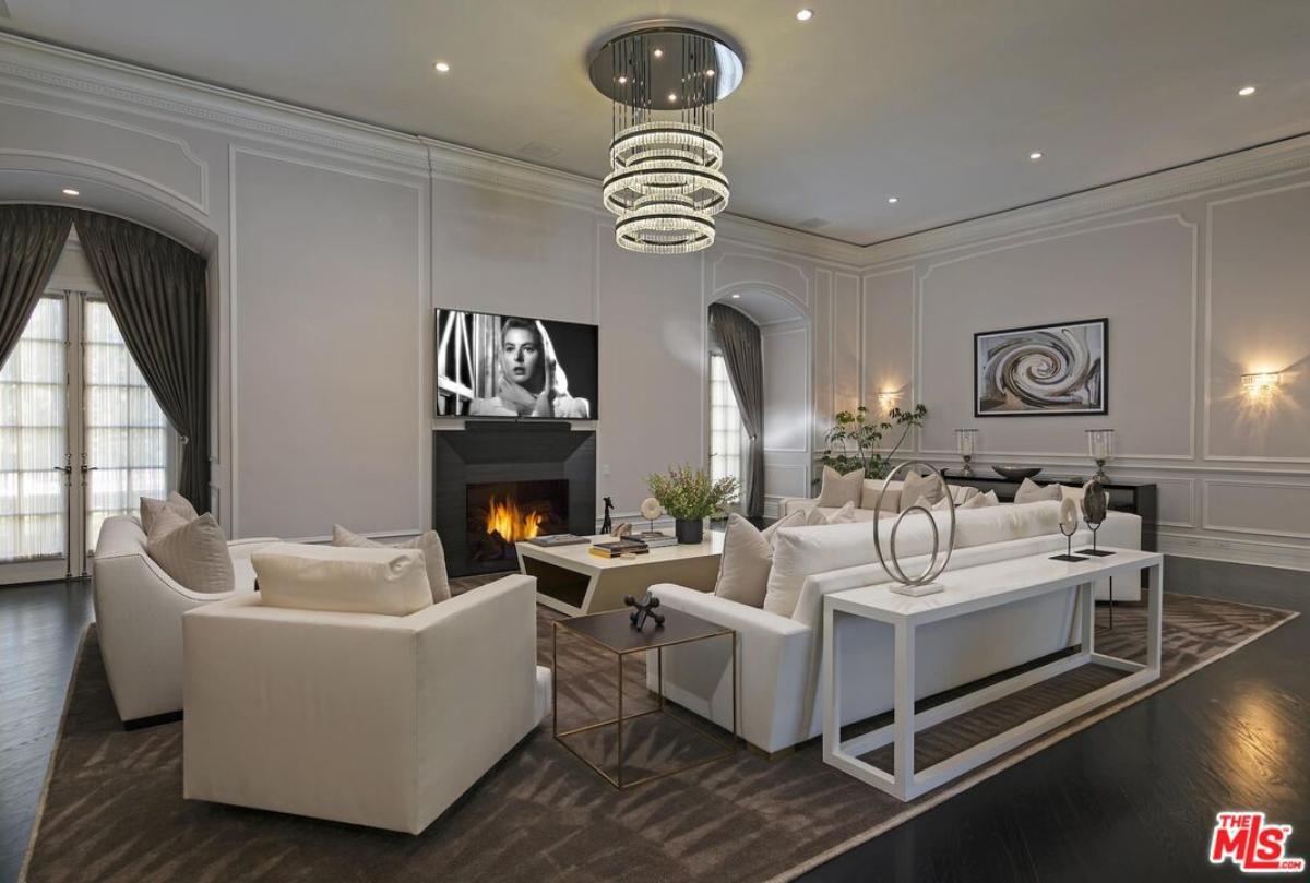 Living room with couches, chandelier and a fireplace.