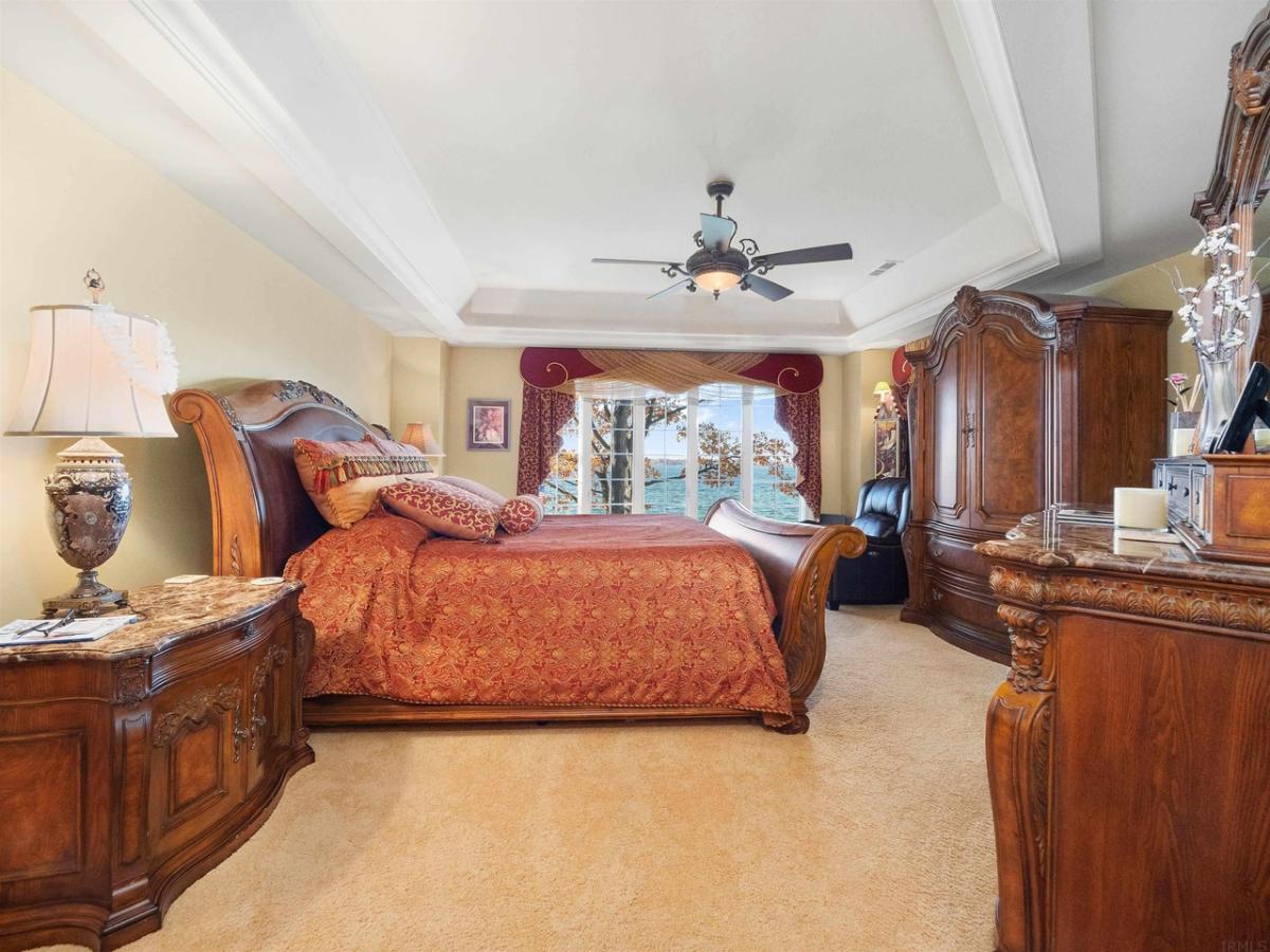 Bedroom with a large bed, glass windows and carpet flooring.