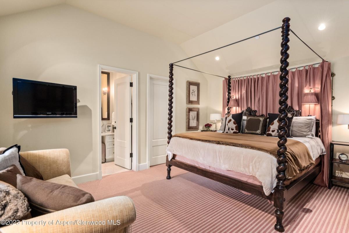 Bedroom with a large bed, chair and carpet flooring.
