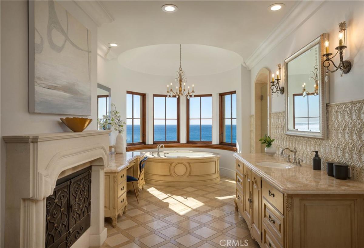 Bathroom with a soaking tub, chandelier, mirror and a fireplace.