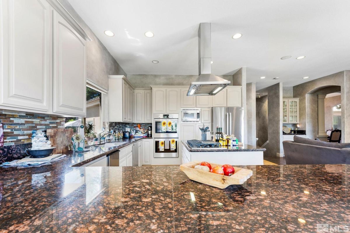 Kitchen with a large island, granite countertops, custom lights and custom cabinets.