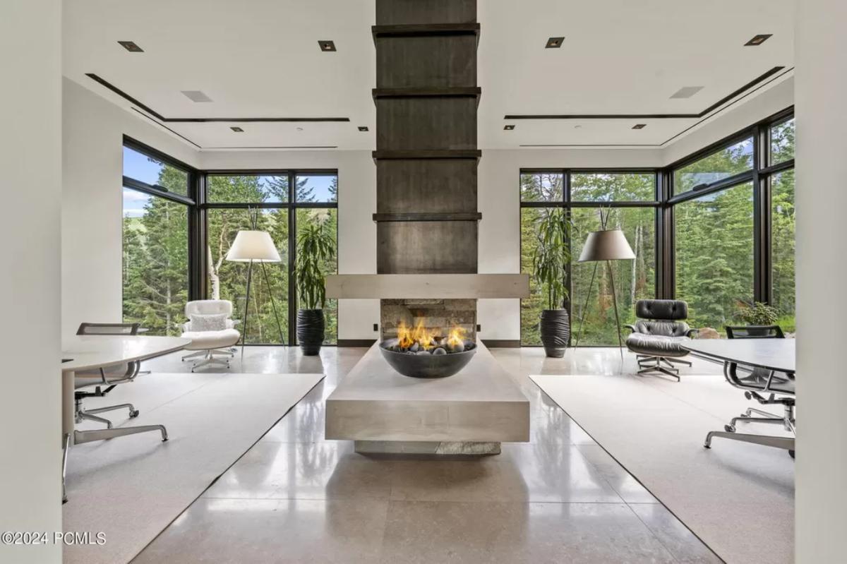 Sitting area with chairs, glass windows and a fireplace.