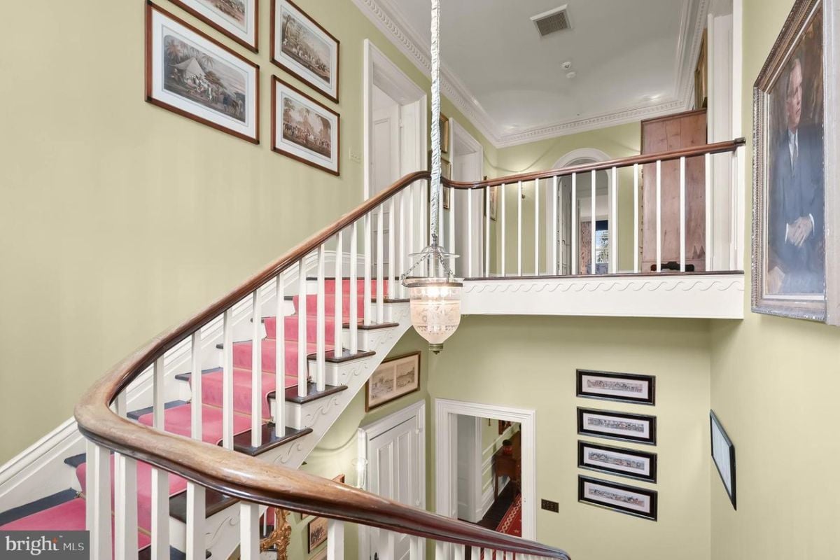 The staircase in the building, with a light hanging from the ceiling, features indoor stairs with a handrail and baluster for support.