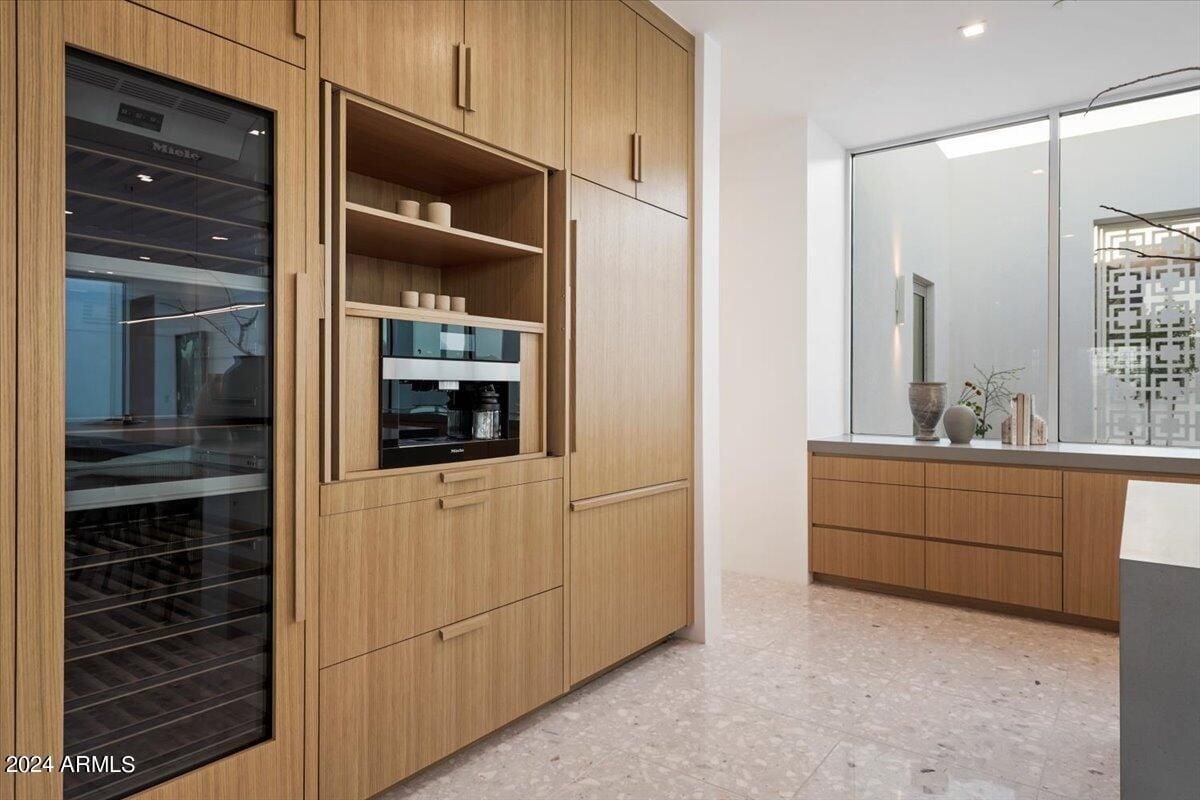 A kitchen with a tiled floor, wooden cabinets, and kitchen appliances.