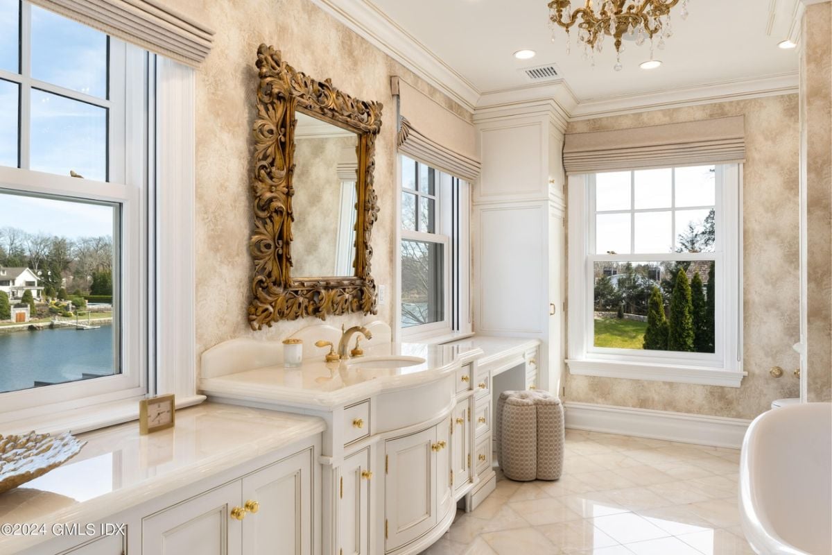 A bathroom featuring a tiled floor, window, mirror, countertops, sink, cabinets, and a white ceiling.