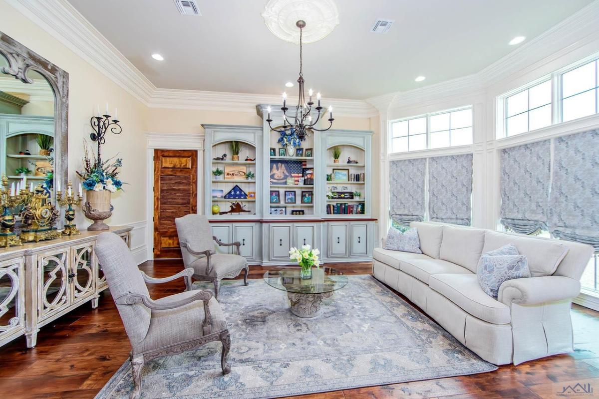 Family room with a couch, chairs, chandelier and a large rug.