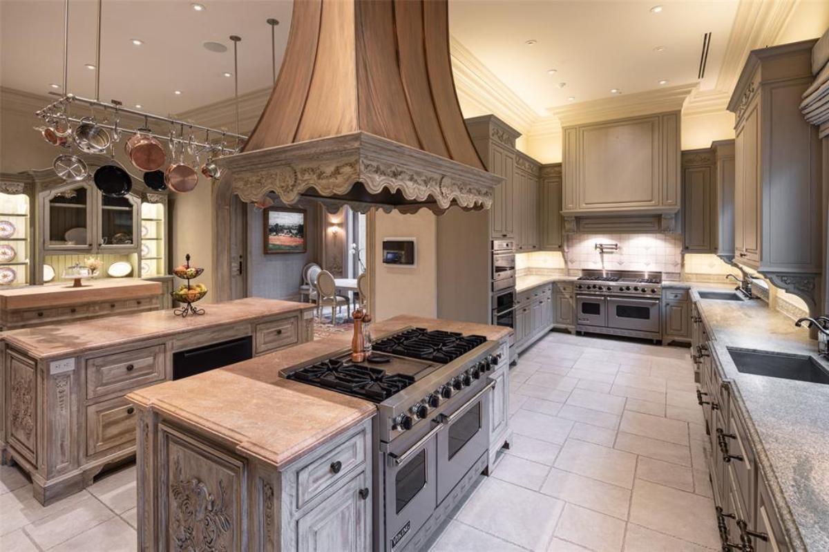 Kitchen with a large island, tile flooring, custom lights and custom cabinets.
