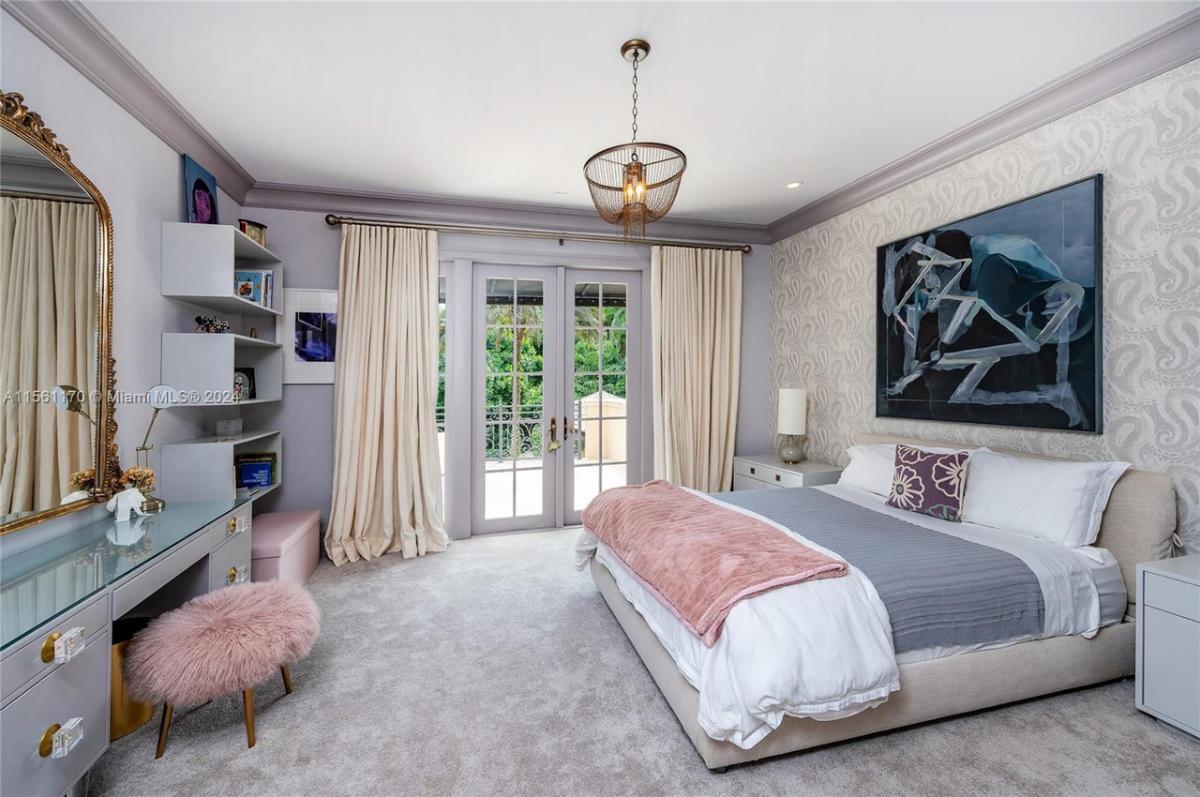 Bedroom with carpet flooring, chandelier and glass doors.