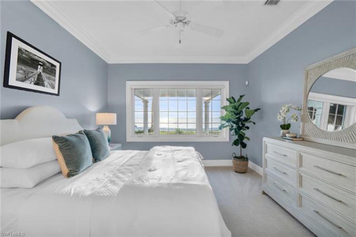 Bedroom with a large bed, carpet flooring and glass windows.