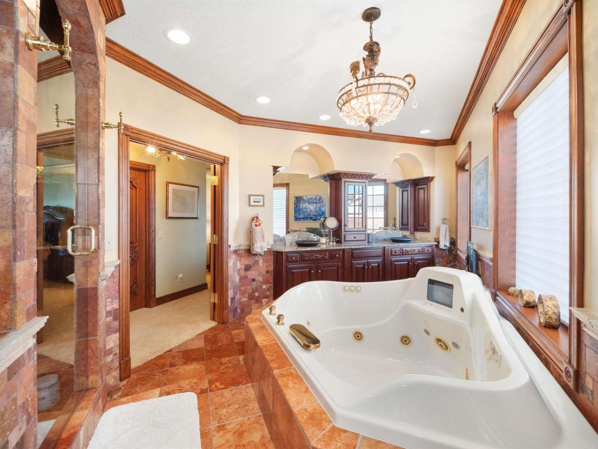 Bathroom with a sinks, soaking tub and a chandelier.